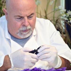 Puede incluir: Un alicate de corte de metal negro sostenido por manos con guantes de l&aacute;tex blancos. La herramienta cuenta con un mecanismo de resorte y puntas afiladas, dise&ntilde;adas para tareas de corte de precisi&oacute;n. Los mangos negros son ergon&oacute;micos y texturizados.