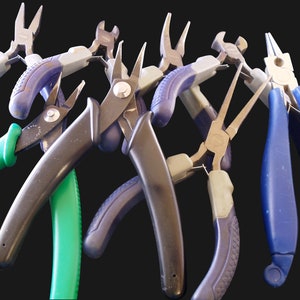 Puede incluir: Una colecci&oacute;n de varios alicates de metal con mangos ergon&oacute;micos en azul, verde y negro. El conjunto incluye alicates de punta fina, cortadores de alambre y alicates de punta plana con agarres texturizados, dispuestos en abanico.