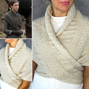 May include: A cream-colored knitted wrap featuring a wide shawl collar and a textured diagonal stitch pattern. The garment is designed to cross over the chest, providing a layered look with a thick, ribbed border along the neckline and edges.