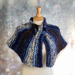 May include: A blue, brown, and white striped knitted shawl with two blue buttons.