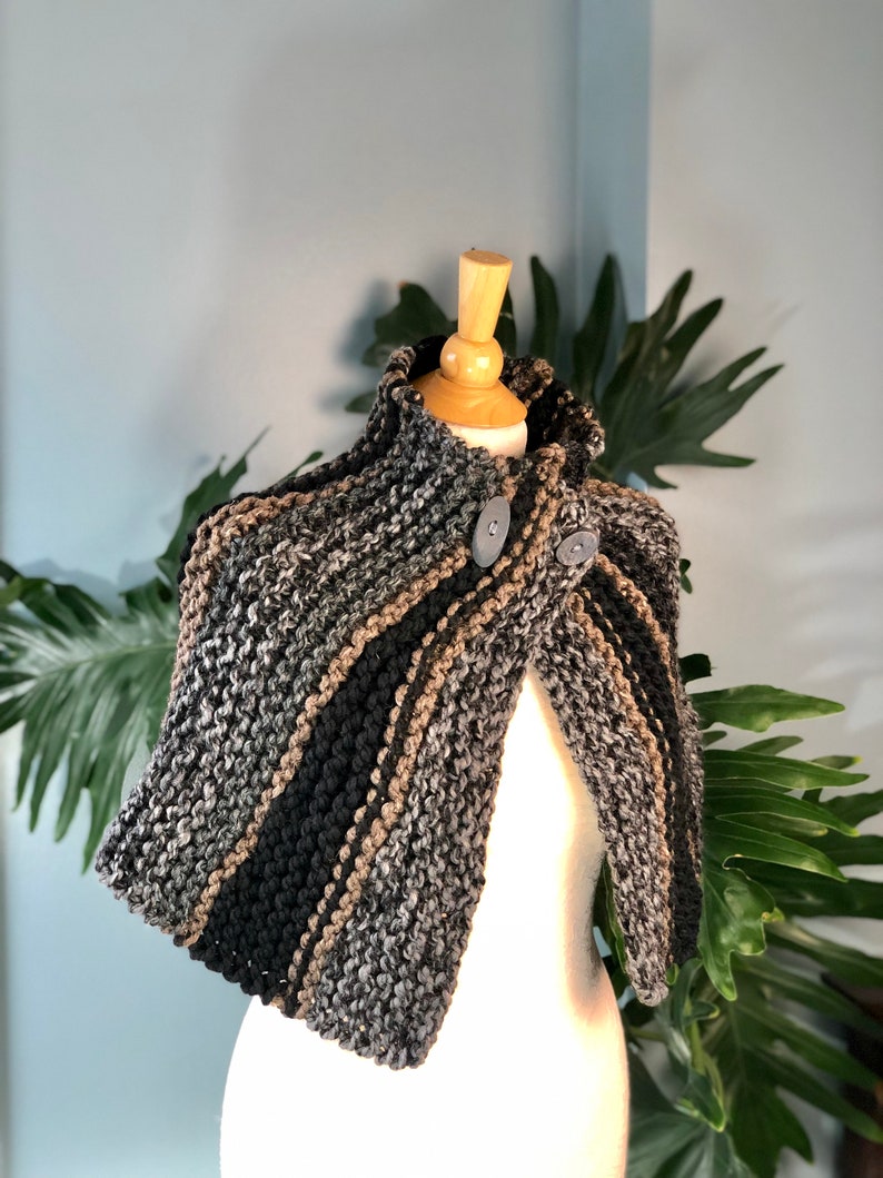 May include: A gray, black, and brown striped knitted cape with a high collar and two buttons.