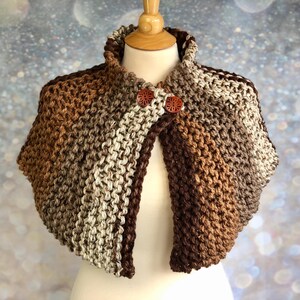 May include: A brown, beige, and cream striped knitted shawl with a high collar and two wooden buttons.
