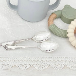 May include: Two silver spoons with personalized engravings. The first spoon says "Grady" with a heart symbol. The second spoon says "Leo" with a heart symbol.