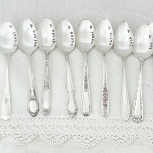 May include: Ten silver spoons with personalized names engraved on the front. The names are Gianni, Maisy, Grady, Hanna, Naomi, Marin, Jack, and Leo.