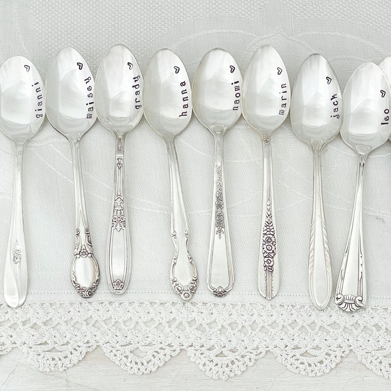 May include: Ten silver spoons with personalized names engraved on the front. The names are Gianni, Maisy, Grady, Hanna, Naomi, Marin, Jack, and Leo.