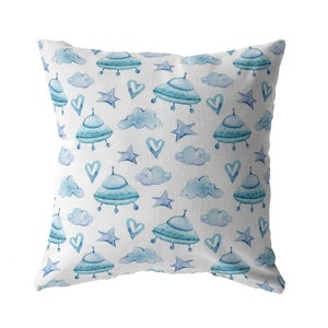 May include: A white pillow with a blue and white pattern of clouds, stars, and flying saucers. The pattern is repeated across the entire pillow.