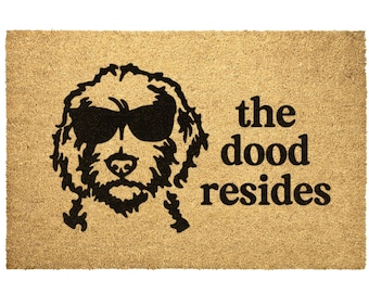 May include: A brown doormat with a black silhouette of a dog wearing sunglasses and the text "the dood resides".
