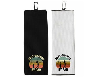 May include: Two black and white golf towel with a vintage design. The towels feature a golfer silhouette with the text "Best Grampy By Par".