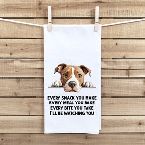 May include: A white kitchen towel with a brown and white pit bull dog peeking over the top. The text on the towel reads "Every snack you make, every meal you bake, every bite you take, I'll be watching you."