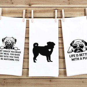 May include: Three white kitchen towels with black pug dog illustrations and text. The first towel says "Every snack you make, every meal you bake, every bite you take, I'll be watching you". The second towel has a silhouette of a pug with a heart on its chest. The third towel says "Life is better with a pug".