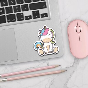 May include: A sticker featuring a cartoon unicorn with a rainbow mane and tail. The unicorn is sitting down with its eyes closed and a smile on its face. The sticker is on a white background.