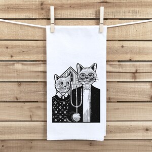 May include: Black and white illustration of two cats standing side-by-side. The cat on the left is wearing a polka dot shirt and the cat on the right is wearing a collared shirt and holding a pitchfork. The cats are standing in front of a small house.