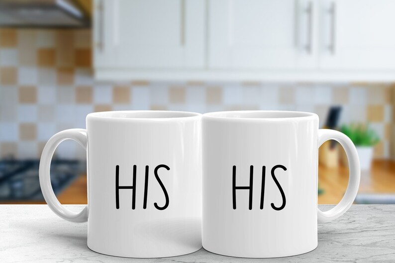 May include: Two white ceramic mugs with black lettering. The mugs are side by side and both say "HIS" on them.