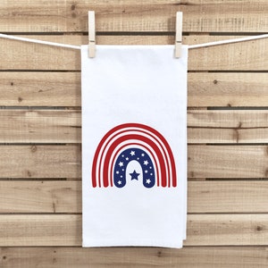 May include: A white kitchen towel with a red, white, and blue rainbow design. The rainbow has a star in the center.