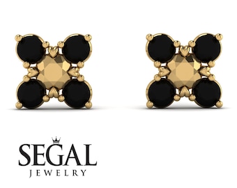 May include: A pair of gold earrings with black gemstones set in a square shape. The earrings have a delicate design with small hearts around the gemstones.