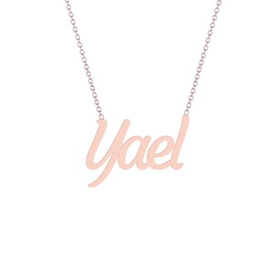 Puede incluir: Un collar de oro rosa con el nombre "Yael" en cursiva. El colgante est&aacute; suspendido de una delicada cadena. El collar se muestra sobre un fondo blanco.