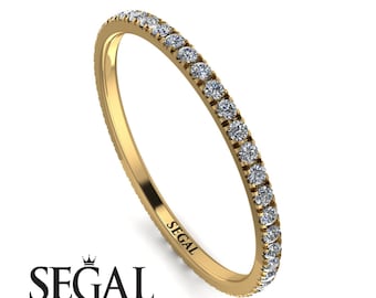 Könnte beinhalten: Ein goldener Bandring mit einer durchgehenden Reihe kleiner, klarer Edelsteine. Der Ring ist vor einem weißen Hintergrund platziert. Das Wort "SEGAL" ist auf dem Ring eingraviert.