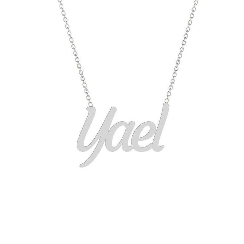 Puede incluir: Un collar plateado con el nombre "Yael" en cursiva. El colgante est&aacute; unido a una fina cadena. La joya se muestra sobre un fondo blanco.