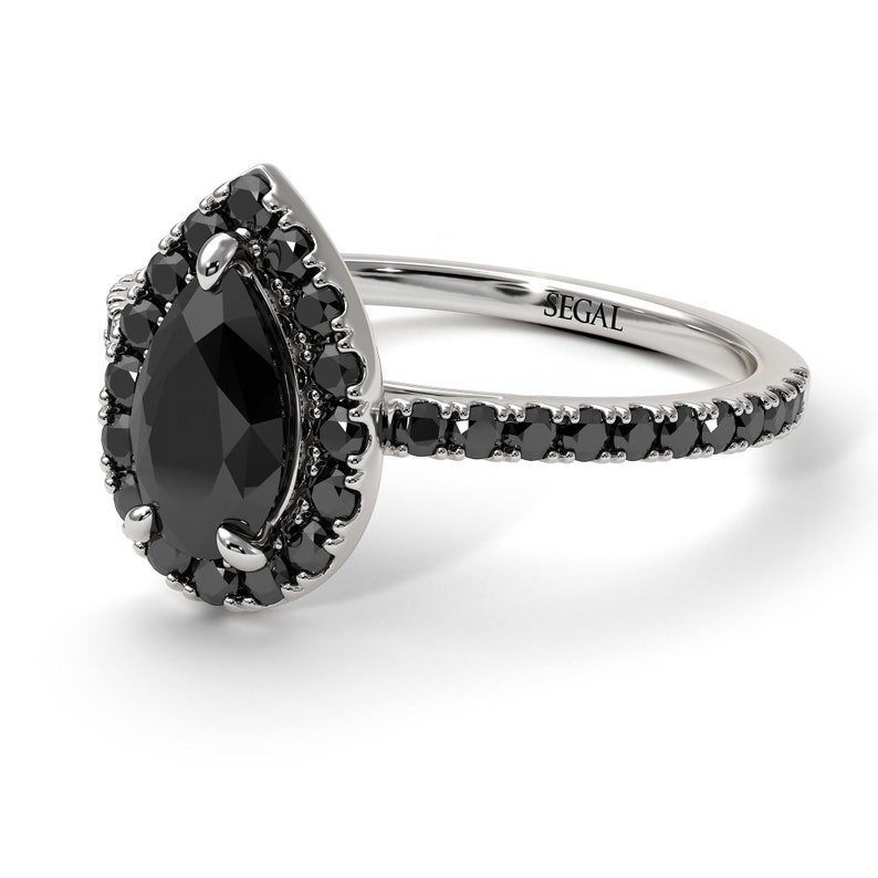 May include: A pear-shaped black diamond engagement ring with a halo of smaller black diamonds. The ring band is also set with black diamonds and is marked "SEGAL".