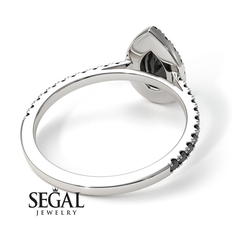 May include: A pear-shaped black diamond engagement ring with a pave diamond band. The ring is set in white gold and features a delicate, intricate design.
