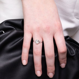 May include: A silver ring with an oval-shaped center stone and two smaller triangular stones on either side.