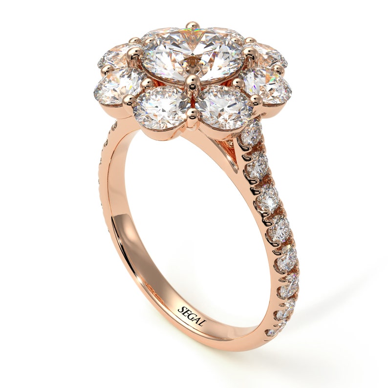 May include: A rose gold engagement ring with a large round center diamond surrounded by smaller diamonds in a flower shape. The band is also set with diamonds.