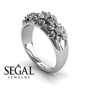 May include: A silver ring with a floral design featuring three diamonds. The ring is engraved with the word "SEGAL".