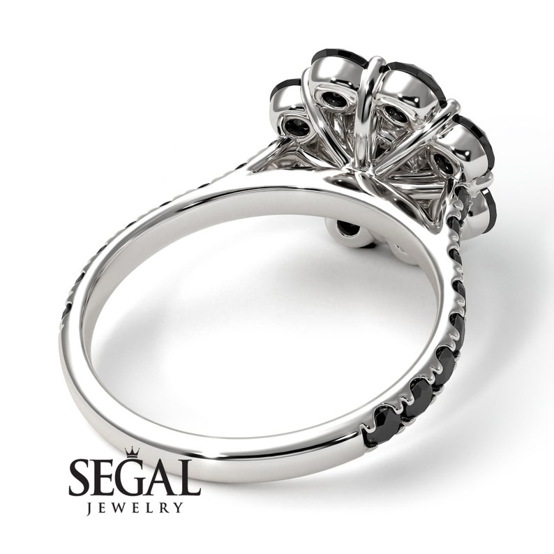 May include: A silver ring with a cluster of black diamonds in the center and a band of smaller black diamonds around the ring.