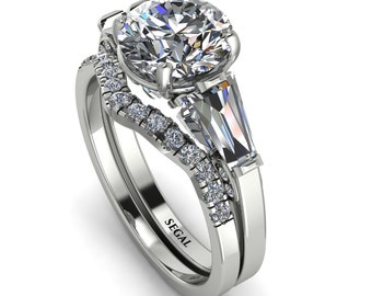 May include: A white gold engagement ring set with a large round centre stone and two baguette side stones. The band is set with smaller round stones. The ring is engraved with the word "SEGAL".