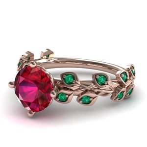 May include: A rose gold ring with a large red ruby gemstone and a delicate vine design with emerald green stones.