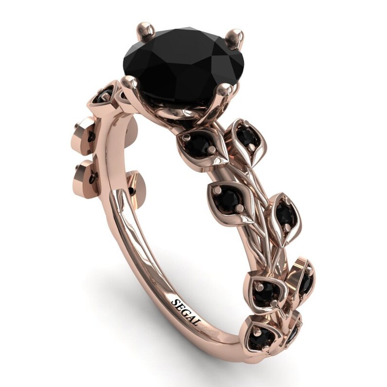 May include: A rose gold engagement ring with a black diamond center stone and black diamond accents on the band. The band is decorated with a vine design.