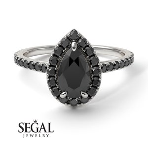 May include: A pear-shaped black diamond engagement ring with a halo of smaller black diamonds. The ring has a pave setting with black diamonds on the band.