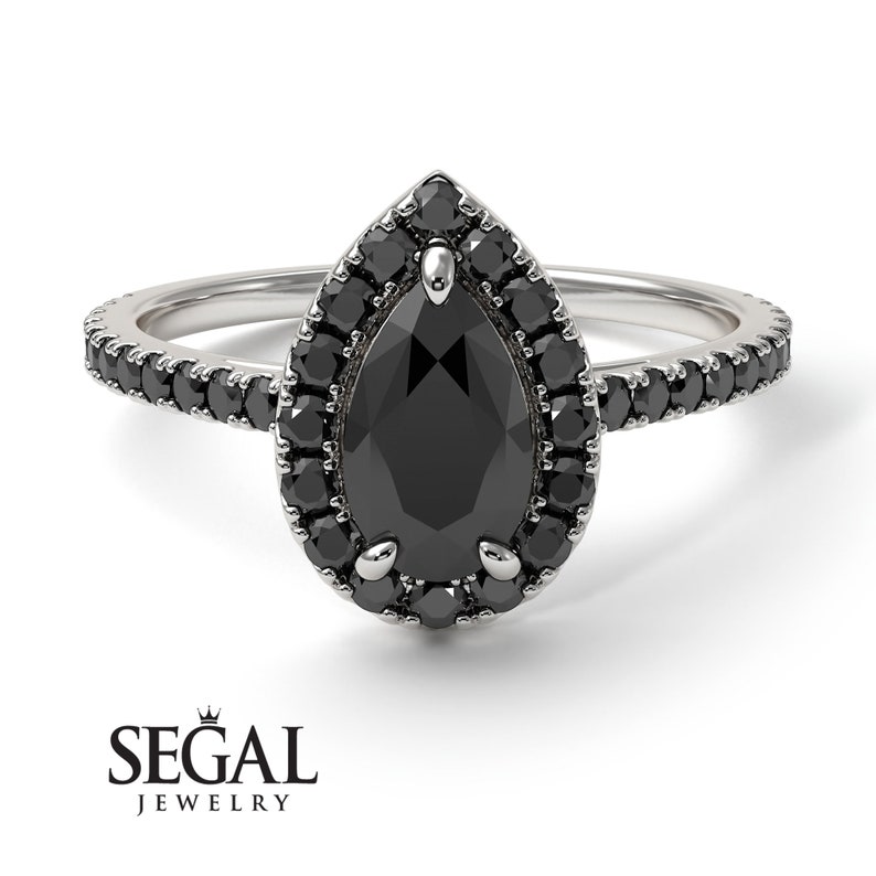 May include: A pear-shaped black diamond engagement ring with a halo of smaller black diamonds. The ring has a pave setting with black diamonds on the band.