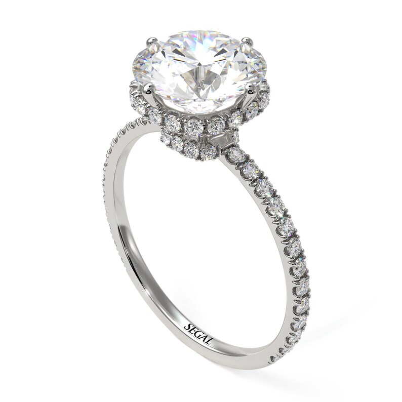 K&ouml;nnte beinhalten: Ein Verlobungsring aus Wei&szlig;gold mit einem gro&szlig;en runden Diamanten in der Mitte, der von einem Heiligenschein aus kleineren Diamanten umgeben ist. Die Ringschiene ist ebenfalls mit kleineren Diamanten besetzt.