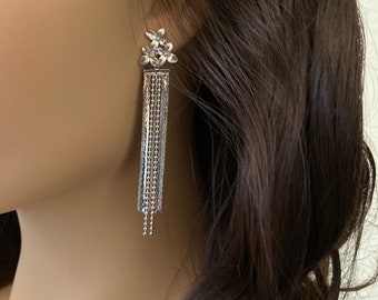 May include: Silver dangle earrings with a cluster of small flower charms at the top and a long chain tassel.