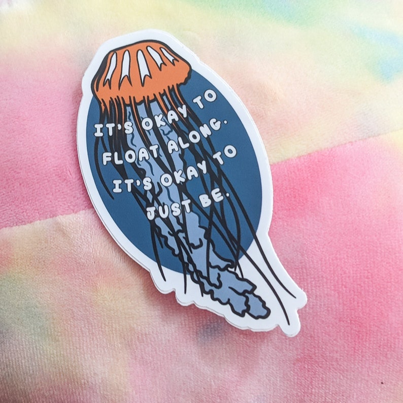 May include: A blue and orange sticker with a jellyfish illustration and the text "It's okay to float along. It's okay to just be."