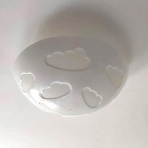 May include: White ceiling light fixture with a rounded shape and a design of five cloud cutouts.