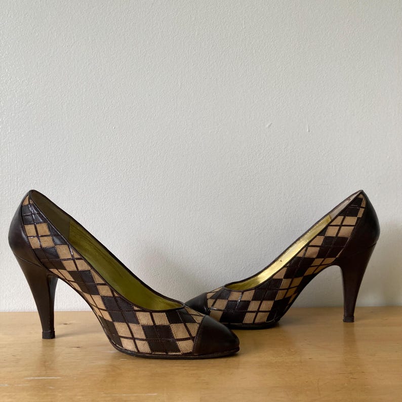 Puede incluir: Un par de zapatos de tac&oacute;n alto marrones y beige. Los zapatos presentan un patr&oacute;n de diamantes en la parte superior y un tac&oacute;n y puntera de color marr&oacute;n oscuro. Los tacones miden aproximadamente 7.6 cm de alto. El forro interior es de color verde claro.
