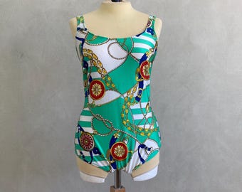 May include: A one-piece swimsuit with a nautical design. The swimsuit features a green background with white stripes and gold chain and rope detailing. Red and blue accents are also present in the design.