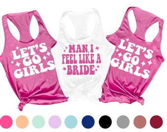 May include: Three tank tops with pink lettering on a white background. The tank tops say "Let's Go Girls", "Man, I Feel Like A Bride", and "Let's Go Girls".
