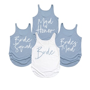 May include: Four tank tops, perfect for a bridal party. Three are a light blue color and say "Bride Squad", "Maid of Honor", and "Bridesmaid" in white script. The fourth tank top is white and says "Bride" in light blue script.