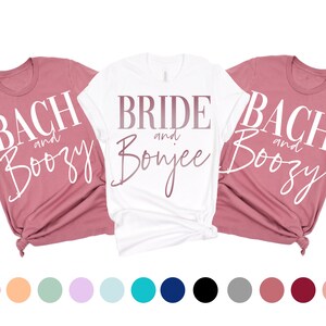 May include: Three white t-shirts with pink and white text. The shirts say "Bach and Boozy", "Bride and Bonjee", and "Bach and Boozy".