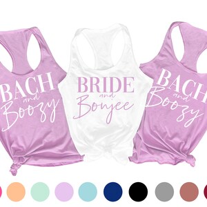May include: Three tank tops with the text "Bach and Boozy", "Bride and Bonjee", and "Bach and Boozy" in white and pink lettering on a lavender and white background. The tank tops are displayed on a white background with a row of colored circles below.