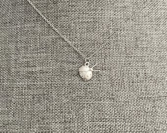 Puede incluir: Un collar de plata con un pequeño colgante de mariquita de plata. La mariquita tiene piedras de cristal transparentes para sus puntos.