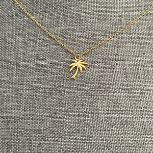 May include: A gold chain necklace with a palm tree pendant.