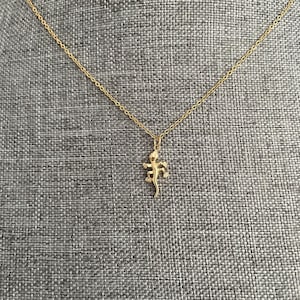 May include: A gold chain necklace with a small gold lizard pendant.