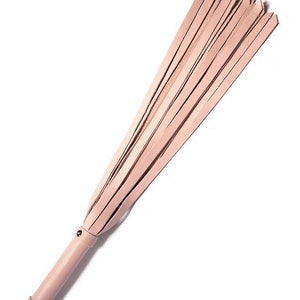 The Stupid Cute Baby Pink Leather Flogger is shown against a blank background. The handle is smooth, cylindrical, and the same color leather as the falls. There is a small loop at the base of the handle.