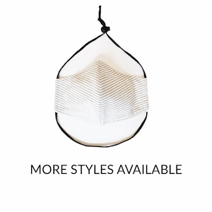 May include: A face mask with a white and gray striped pattern. The mask is held by a black cord and a white backing. The text "MORE STYLES AVAILABLE" is below the mask.
