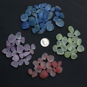 May include: Assortment of sea glass in various colours, including blue, green, purple, and red. The sea glass is arranged in a circle on a black background.