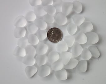 May include: A collection of frosted glass pebbles, approximately the size of a US dime, arranged in a circle on a white background.